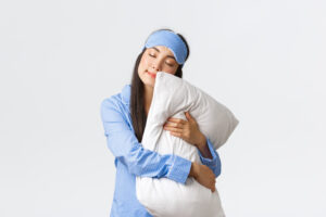 a woman wearing a sleeping mask hugging a pillow