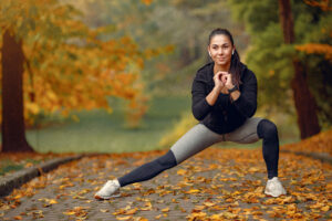 a woman stretching her leg on a path with leaves
